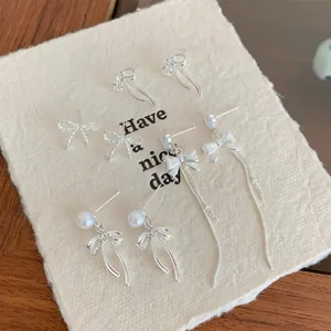 Silver bow earrings set with zircons, pearls and long tassels on white card background