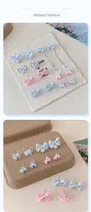 Detailed view of light blue and pink fabric bow earrings with pearls and zircon stones