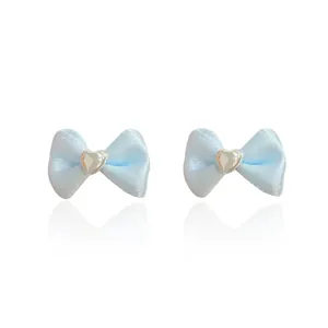 Sweet light blue ribbon bow earrings with silver heart center on white background