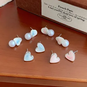 Blue and pink marbled heart stud earrings with pearls on a vintage wooden base