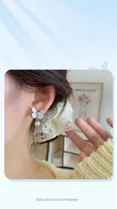 Close-up of a gradient blue butterfly earring with a hanging white pearl tassel detail
