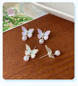 Detail of gradient enamel butterfly earrings with hanging pearls and silver finish
