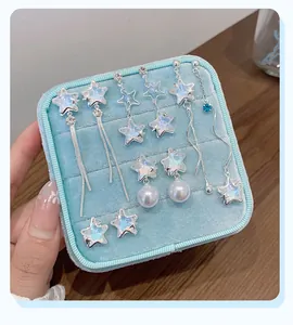 Close-up of five pairs of silver star earrings with pearls in a blue velvet jewelry box