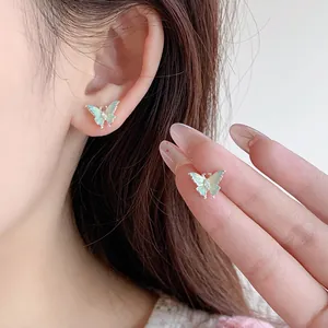 Boucles d'oreilles papillon menthe avec fini perlé portées par un mannequin