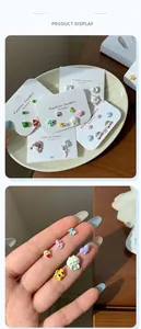 Macro view showing the mini scale of cute cartoon watermelon and bear stud earrings