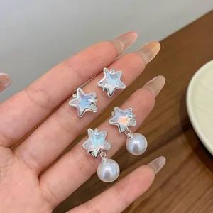 Star-shaped earrings with shimmering opal and pearls on a warm wooden background