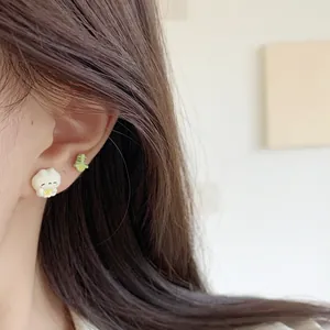 Asymmetric cartoon white girl and green flower stud earrings on female ear