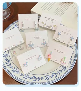 Detailed close-up of cartoon carousel and unicorn enamel earring sets on display cards