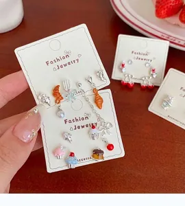 Macro shot of dessert-themed earrings featuring croissant and cherry enamel details