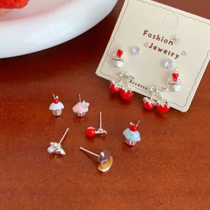 Cute cherry and cupcake enamel stud earring set for women on a warm wood surface