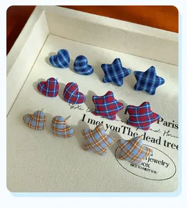 Detailed view of plaid fabric heart and star stud earrings in a vintage jewelry display