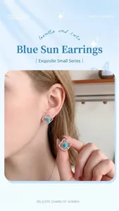 Macro shot of silver sun stud earrings with a central round sky blue stone detail