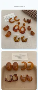 Close-up of vintage amber resin earrings in C-shape and geometric styles on beige fabric