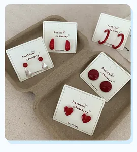 Macro shot of five pairs of vibrant cherry red geometric earrings on a display card