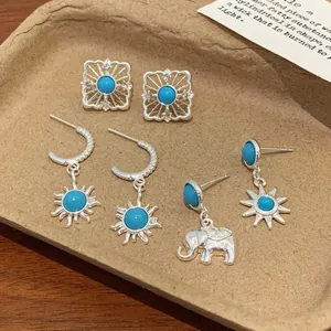 Bohemian silver earrings set with turquoise stones featuring sun and elephant charms