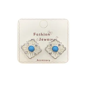 Silver hollow rhombus stud earrings with blue gemstone and sparkling white crystals