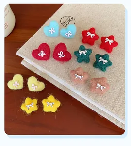 Close-up of colorful plush star and heart earrings with small bow decorations