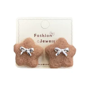Brown fuzzy star stud earrings with silver bows on a minimalist display card