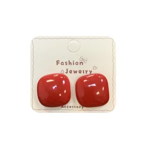 Minimalistische vierkante oorknopjes in glanzend rood op een sieraden displaykaart