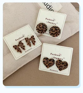 Detail view of leopard print heart and bow stud earrings set with velvet texture