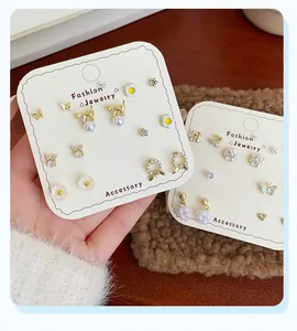 Detail of diverse gold-finish stud earrings featuring pearls, crystals, and animal motifs