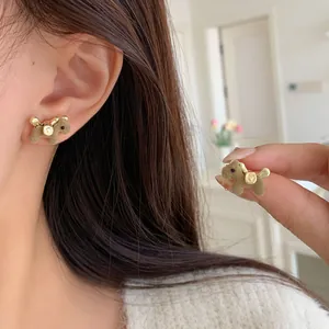 Cute brown flocked puppy stud earrings with gold accents shown on a model for a soft look