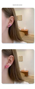 Detailed view of pink butterfly and heart stud earrings set shown on model ear