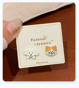 Detail of cute asymmetric cartoon cat and dog stud earrings on a fashion jewelry card