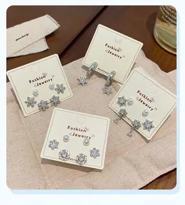 Detailed view of silver snowflake earring set with zircon and pearls on jewelry card