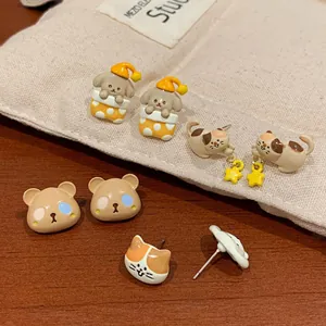 Cute cartoon puppy and cat stud earring set with brown enamel finish on wood background
