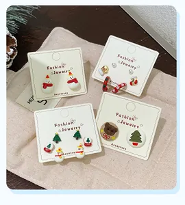 Detailed set of Christmas earrings including snowman and bear on a rustic fabric background