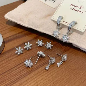Silver snowflake earring set with cubic zirconia stones on dark wood and linen background