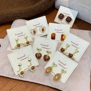 French vintage amber resin heart and faux pearl gold earrings set on fabric background