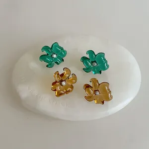 Detalle macro de pendientes de flores de resina ámbar y esmeralda con finos diamantes