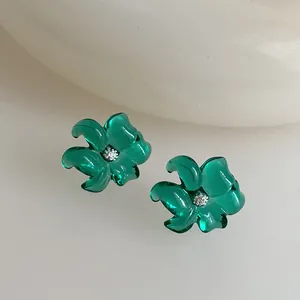 Primer plano de pendientes de flores verde esmeralda en resina con centros de cristal brillo