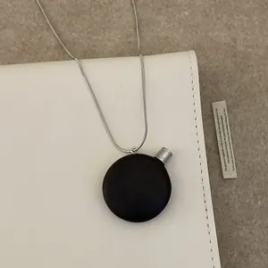 Collier pendentif flacon de parfum en bois rétro avec chaîne argentée sur sac cuir