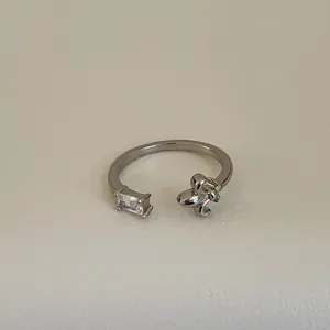 Detailansicht eines silbernen offenen Rings mit rechteckigem Zirkon und Metallelement