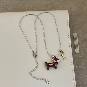 Détail du collier chaîne argenté avec pendentif teckel en émail marron et petit os doré