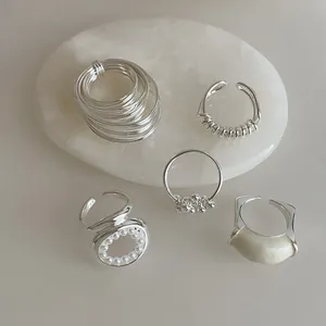 Lot de 5 bagues argentées avec perles et émail présentées sur pierre décorative