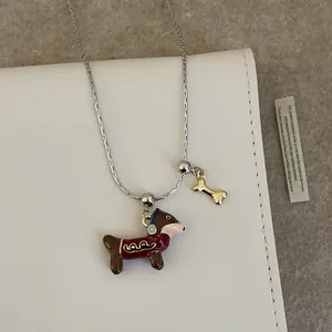 Détail du pendentif teckel et charme d'os sur chaîne argentée sur papeterie esthétique