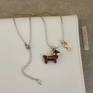 Détail du collier teckel en émail rouge avec un petit pendentif en forme d'os doré