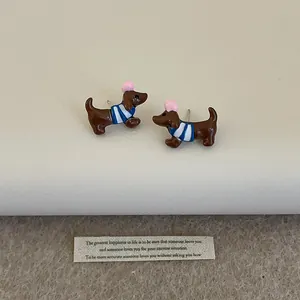 Détail de boucles d'oreilles teckel en résine marron avec vêtements rayés colorés