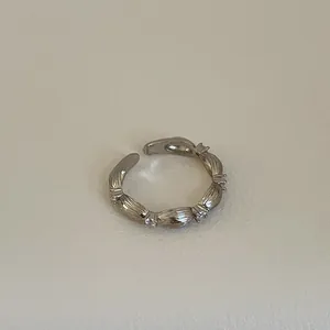 Detailaufnahme eines silbernen verstellbaren Rings mit Bambustextur und Zirkon-Akzenten