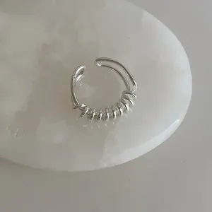 Détail d'une bague ouverte multicouche argentée sur un fond de marbre blanc