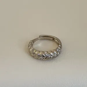 Detailaufnahme des geflochtenen Silberrings mit Zirkonia-Steinen auf beigem Grund