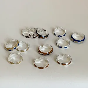 Detail of vintage geometric enamel rings with colorful diamond patterns on beige leather