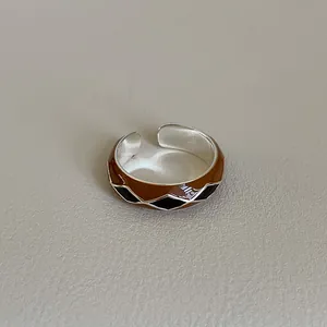 Macro detail of silver adjustable ring featuring brown and black enamel diamond patterns