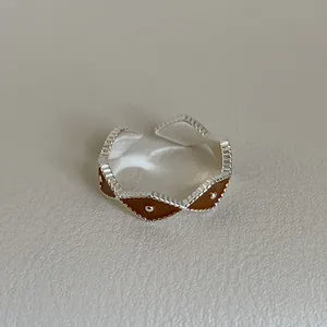 Detail of silver wavy ring with dark brown enamel inlay and central silver bead