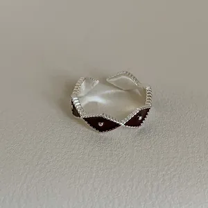 Macro view of vintage silver-tone ring with burgundy enamel diamond patterns and beaded detail