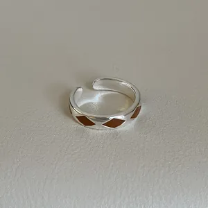 Macro shot of silver ring with brown enamel rhombus pattern and adjustable opening